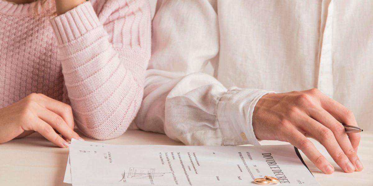 Dokumenty rozwodowe leżące na stole przed kobietą i mężczyzną