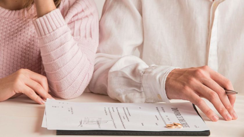 Dokumenty rozwodowe leżące na stole przed kobietą i mężczyzną