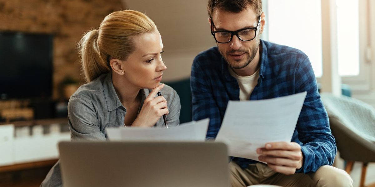 Młoda para analizująca dokumenty finansowe podczas planowania kredytu