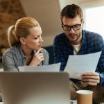 Młoda para analizująca dokumenty finansowe podczas planowania kredytu