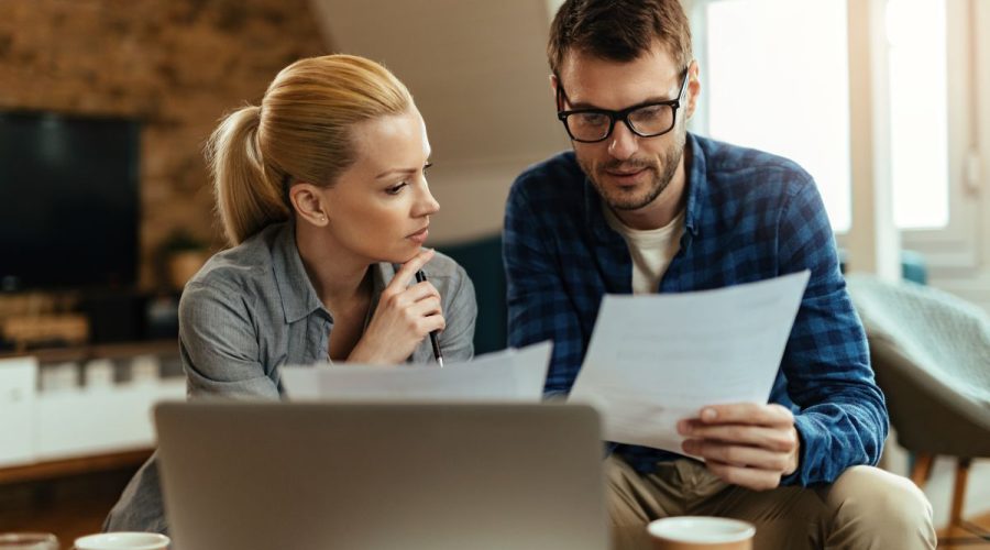 Młoda para analizująca dokumenty finansowe podczas planowania kredytu